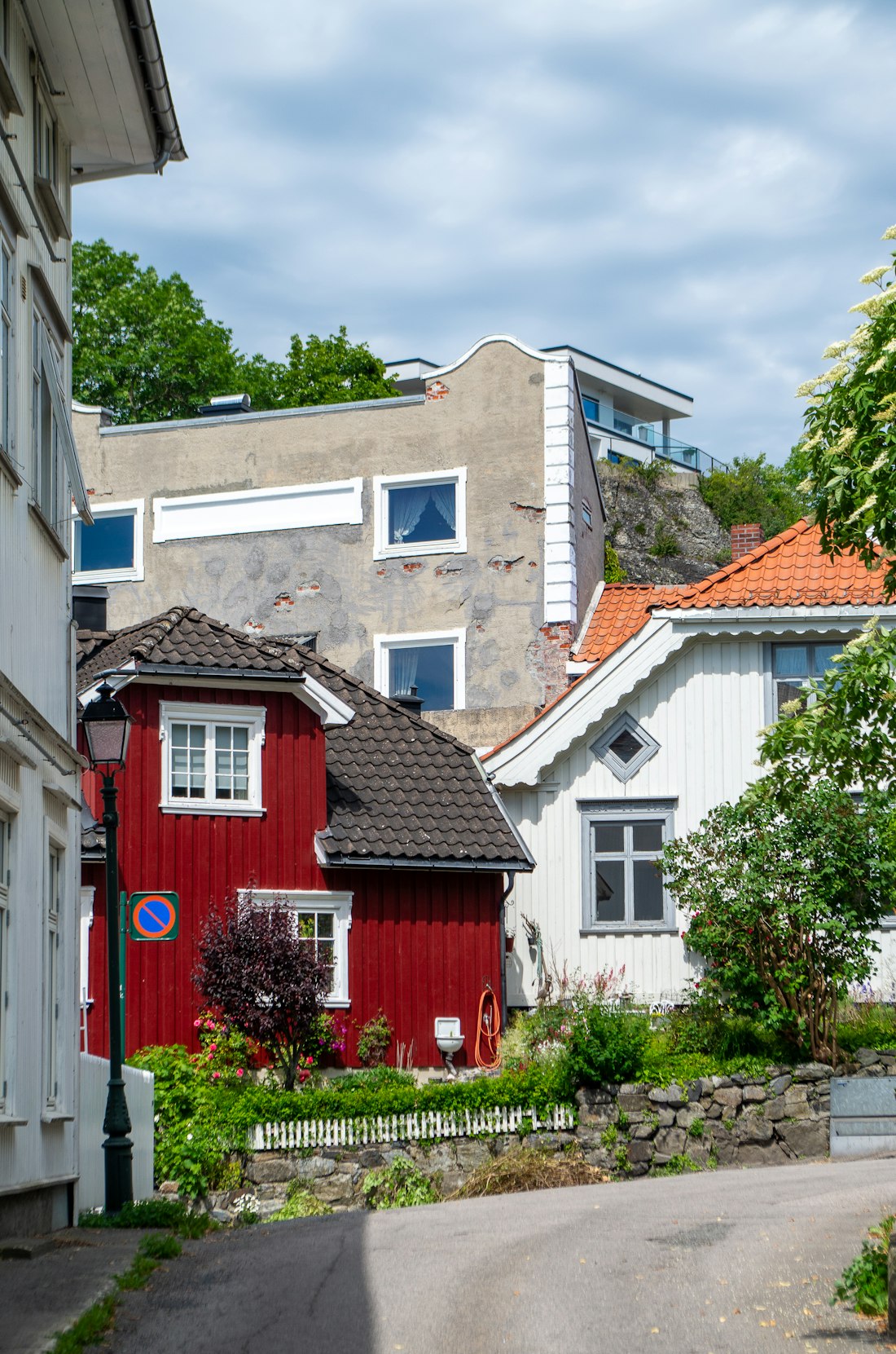 Rødt og hvitt norsk trehus i en frodig hage